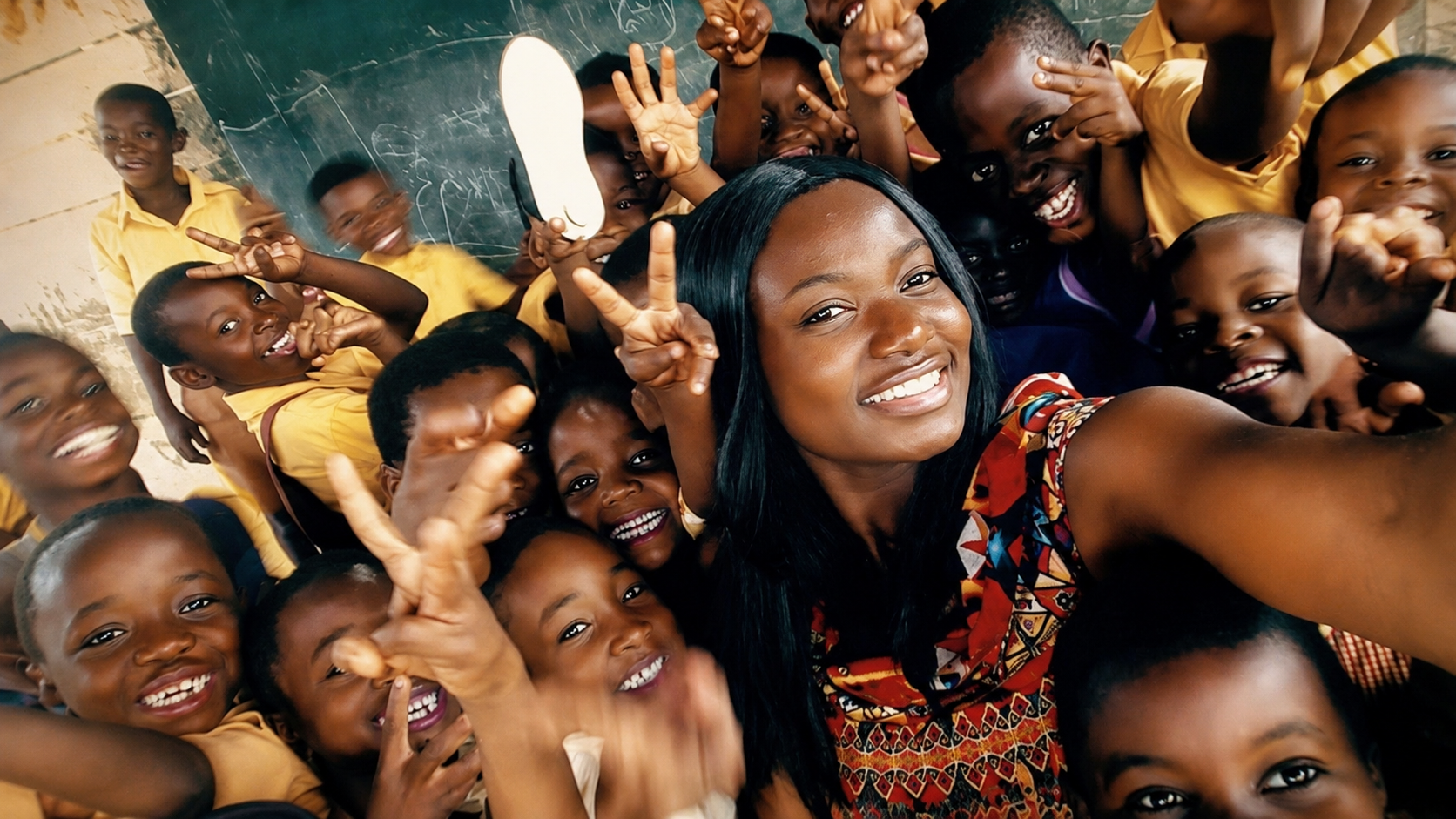 Joyful group selfie with children and a volunteer during a classroom visit