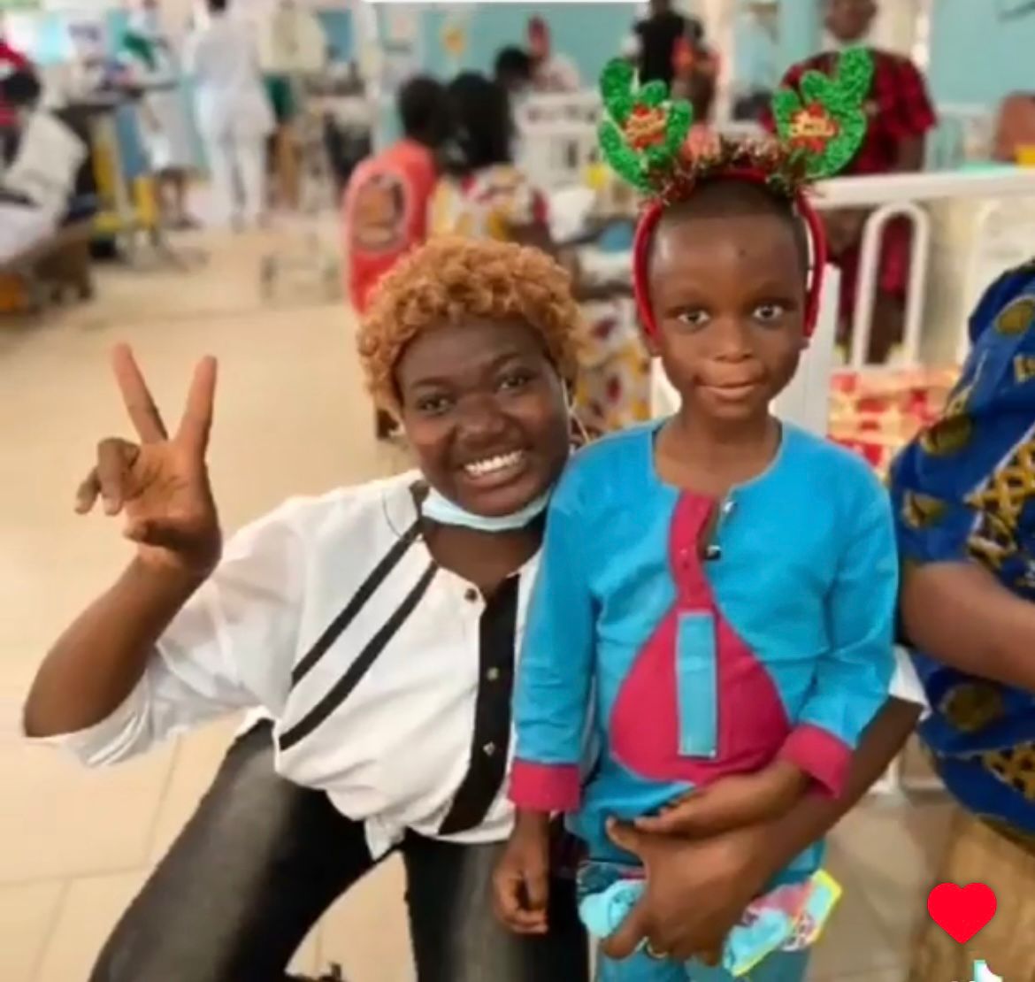 Volunteer smiling with a young patient wearing festive antlers on a hospital ward